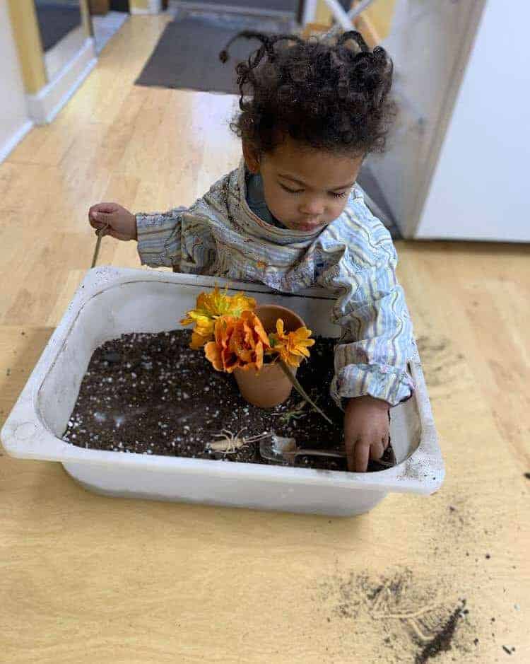 Child planting flowers in a pot at Montessori daycare in Mount Clemens, MI for early childhood education.