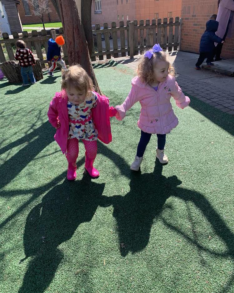 Colorful children holding hands on outdoor playground with shadows, Montessori Stepping Stones daycare & preschool in Mount Clemens, MI.