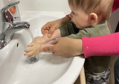 Learning to wash hands at Montessori daycare in Mount Clemens, MI. Child practicing hygiene skills with guidance. Ideal for early childhood development and Montessori educational settings.