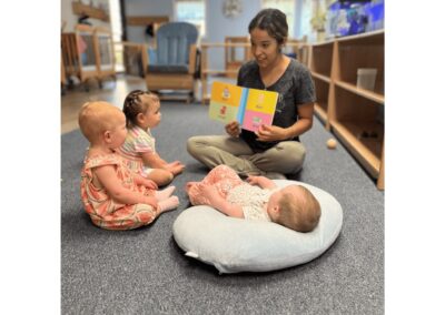 Brightly lit Montessori classroom with young children engaging in a storytime activity with a teacher, promoting early childhood education and social development in Mount Clemens, MI.