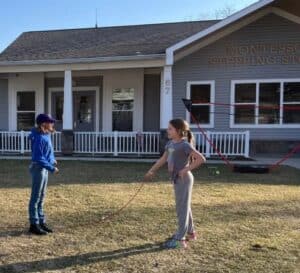 Elementary students playing jump rope outside the Montessori Stepping Stones building in Mount Clemens during summer camp.