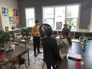 A group of middle school students collaborating on a movie-making project using a ring light and camera, showcasing the creative and technology-integrated Montessori curriculum.
