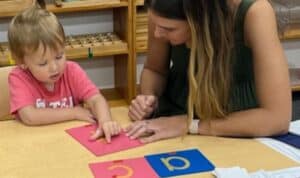 Montessori teacher working one-on-one with a preschool student on letter sounds and phonics in Mount Clemens.