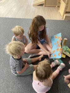 A group of young children and a teacher reading a butterfly book together in a Montessori classroom at Montessori Stepping Stones in Mount Clemens.